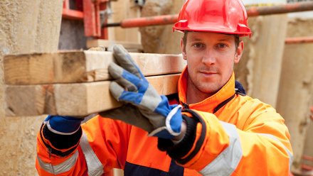 Professional carpenter carrying building materials on a construction site. 