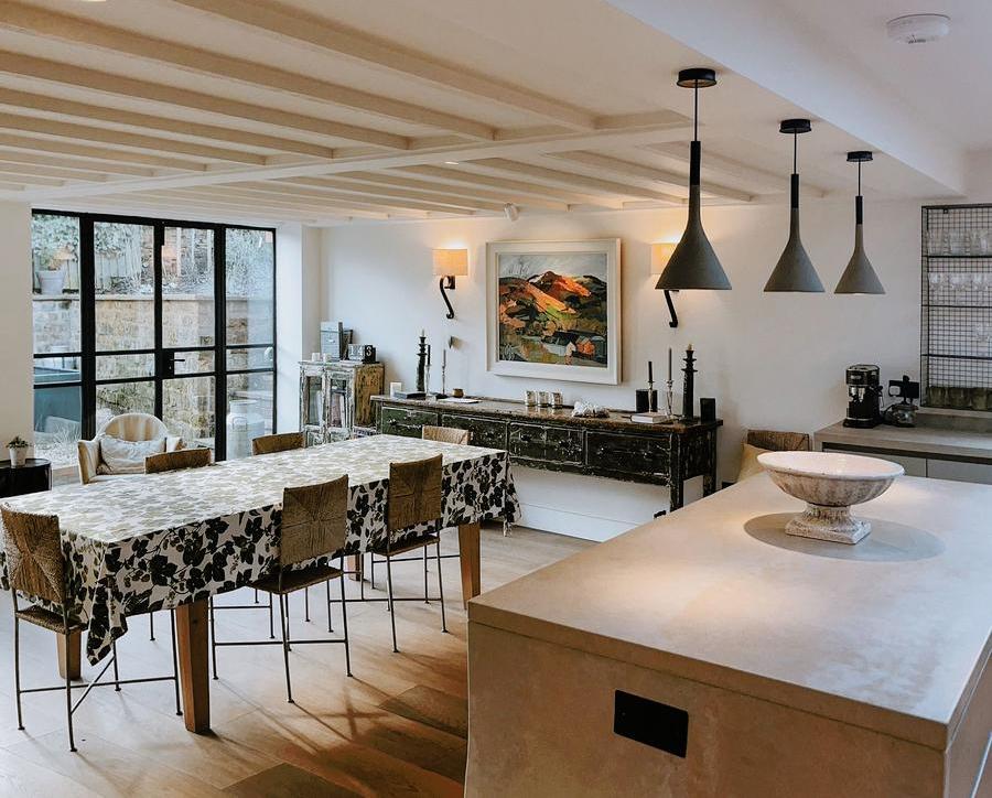 Cosy garage conversion open plan kitchen interior with white beams, beautiful art and three feature lights over an island