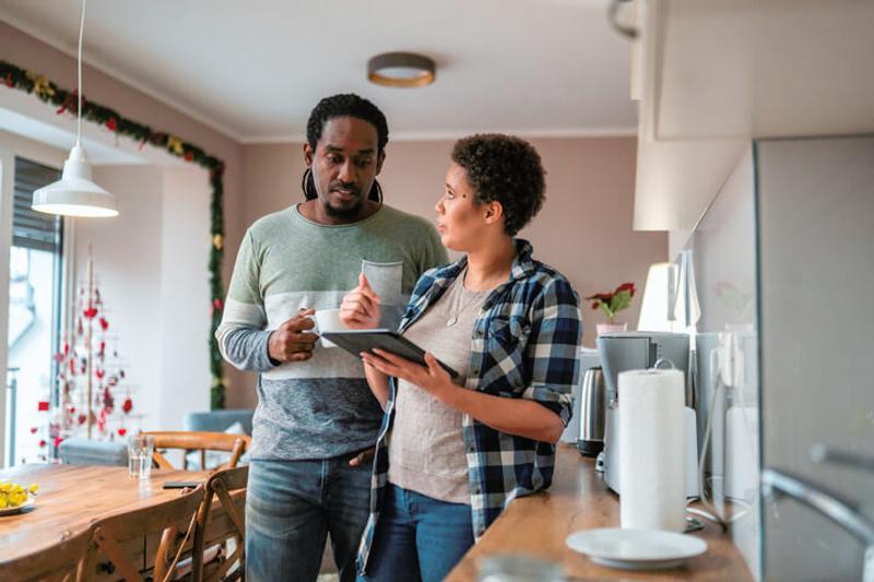 Homeowner couple choosing a builder on a tablet device in their kitchen