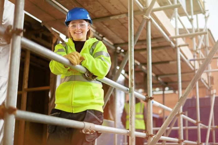 Female builder onsite rests on scaffolding