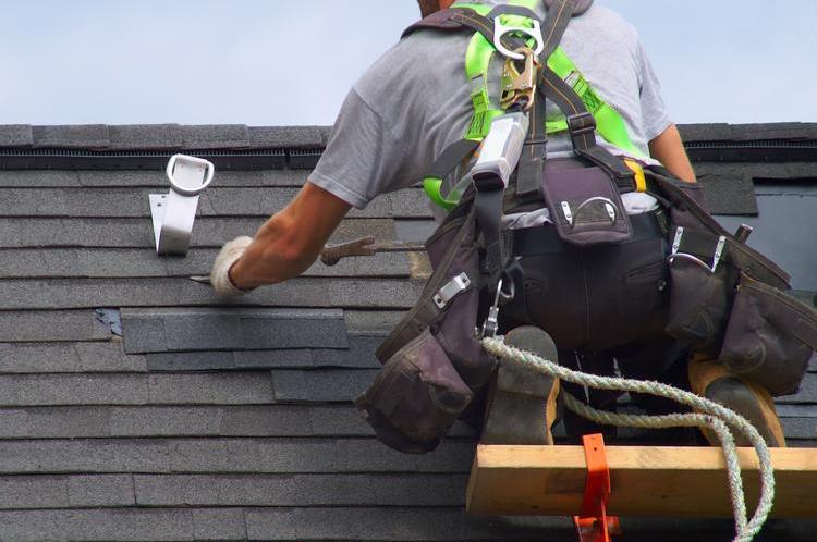 Builder repairing roof with safety tether