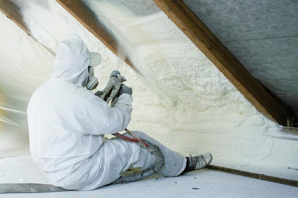 Person in PEE installing spray foam loft insulation